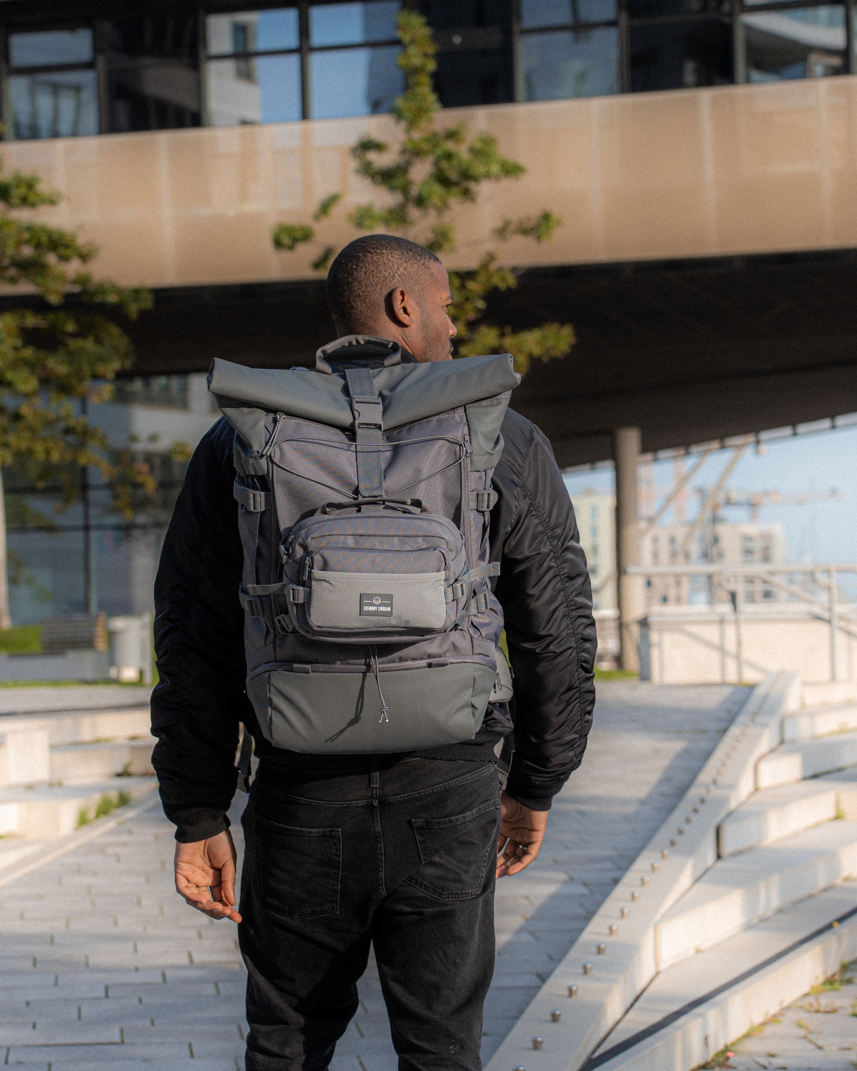 Ein Mann steht mit dem Allen XL Travel Rucksack vor der Hafencity Universität in Hamburg
