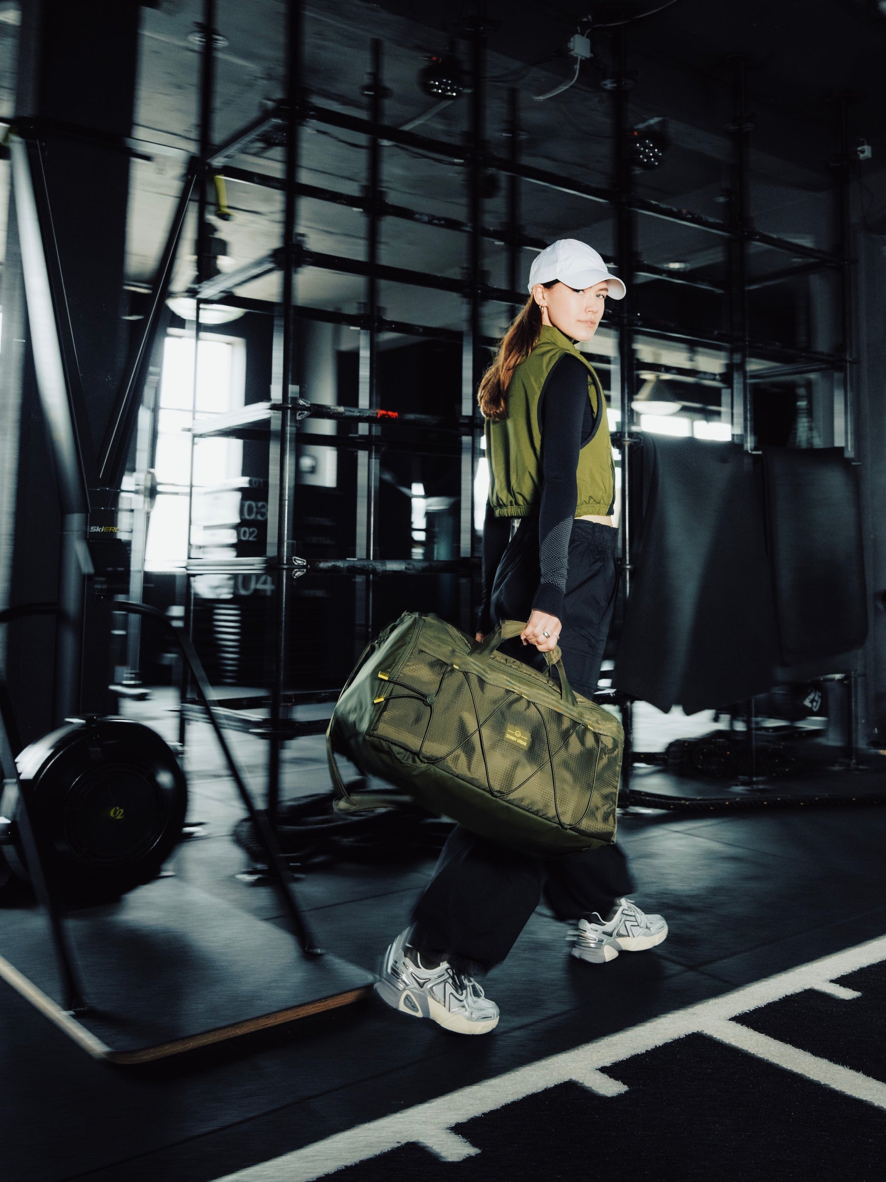 Frau ist im Fitnessstudio und läuft mit einer Johnny Urban Sporttasche in der Hand.