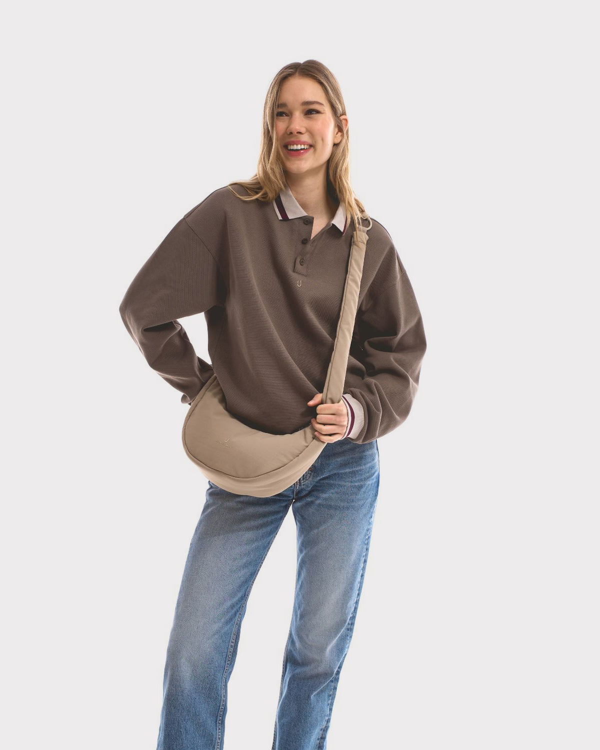 Unser weibliches Model präsentiert sich hier mit der Half-Moon-Bag "Lou Medium" in beige.