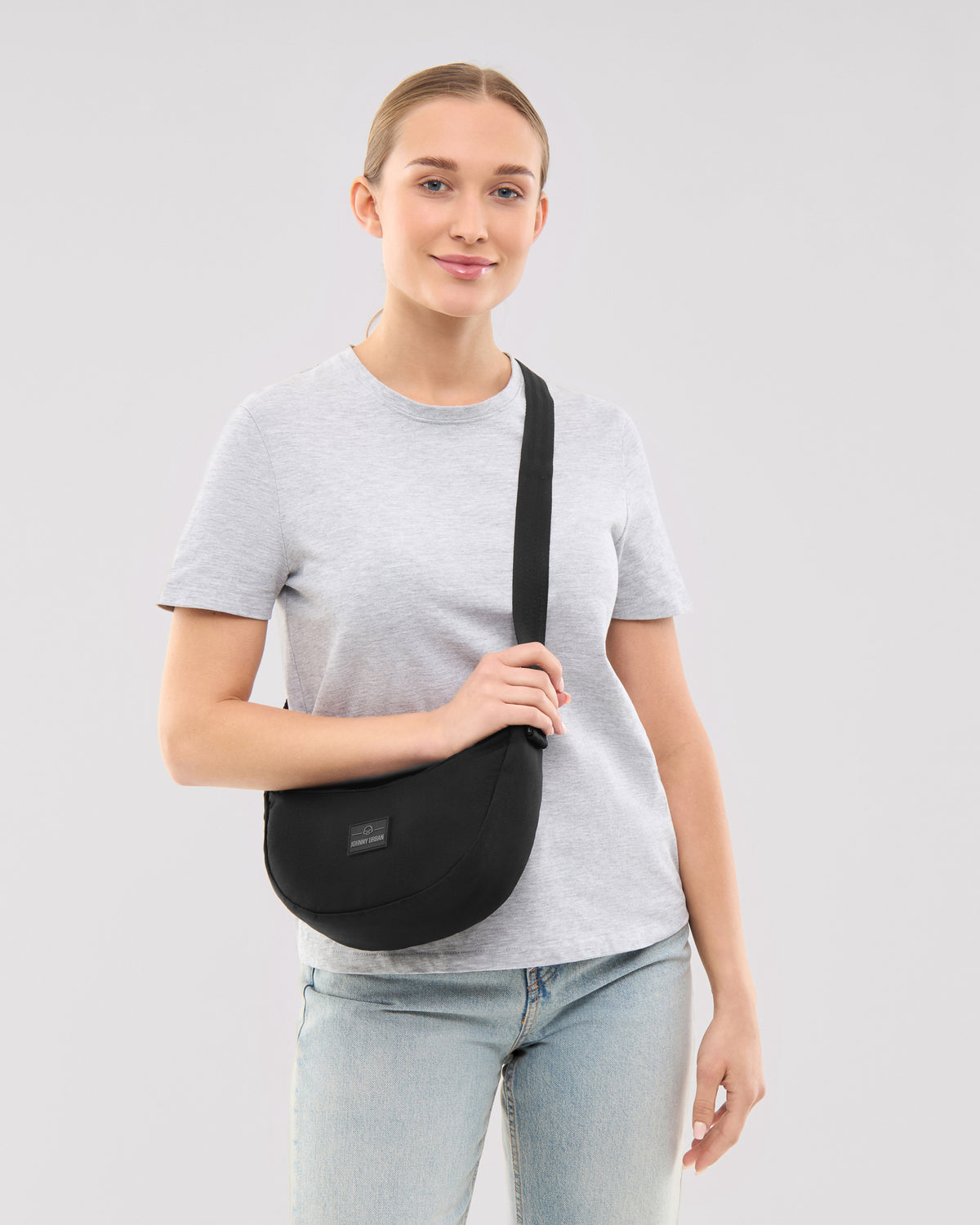 Dame trägt schwarze Half Moon Bag 'Ally Small' von Johnny Urban mit grauem T-Shirt und Jeans