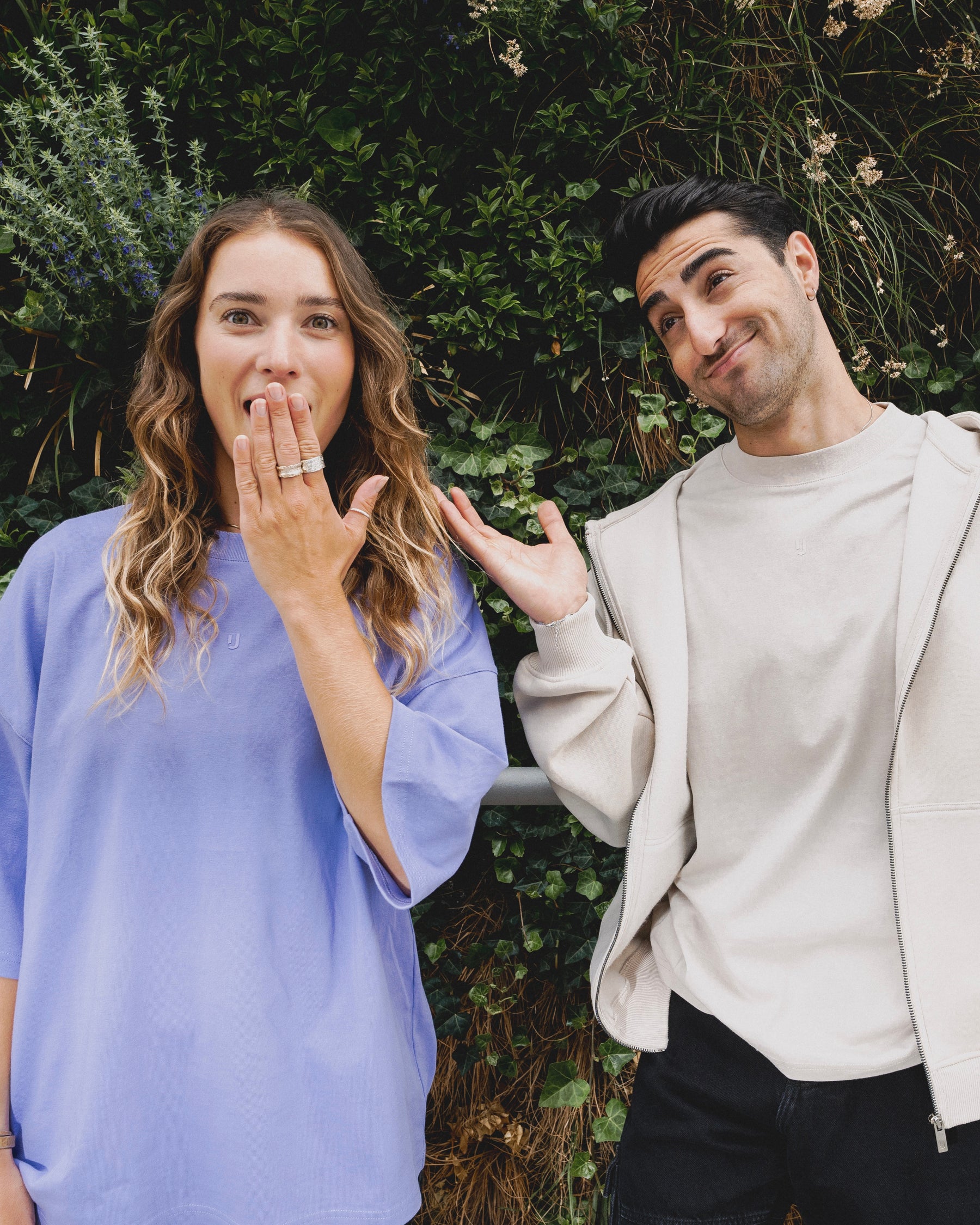 Eine Frau, die sich die Hand vor dem Mund hält, und ein Mann, der die Achseln hoch zieht.