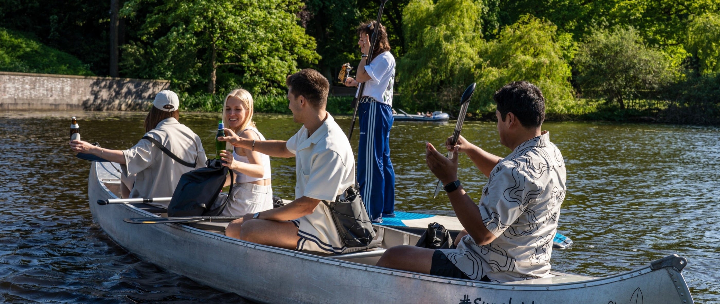 5 Freunde sind mit Kanu und Stand-Up-Paddle-Board auf der Hamburger Alster unterwegs und genieĂźen das Wetter.