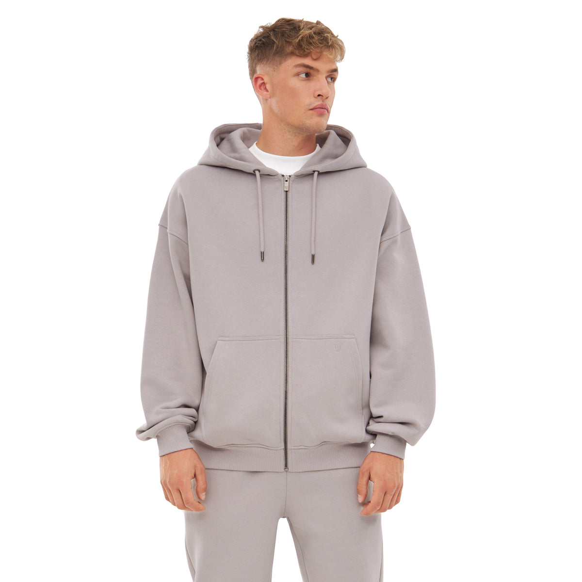Mann trägt oversized Zip Hoodie 'Caleb' in Grau mit Kapuze, Reißverschluss und Kängurutaschen.