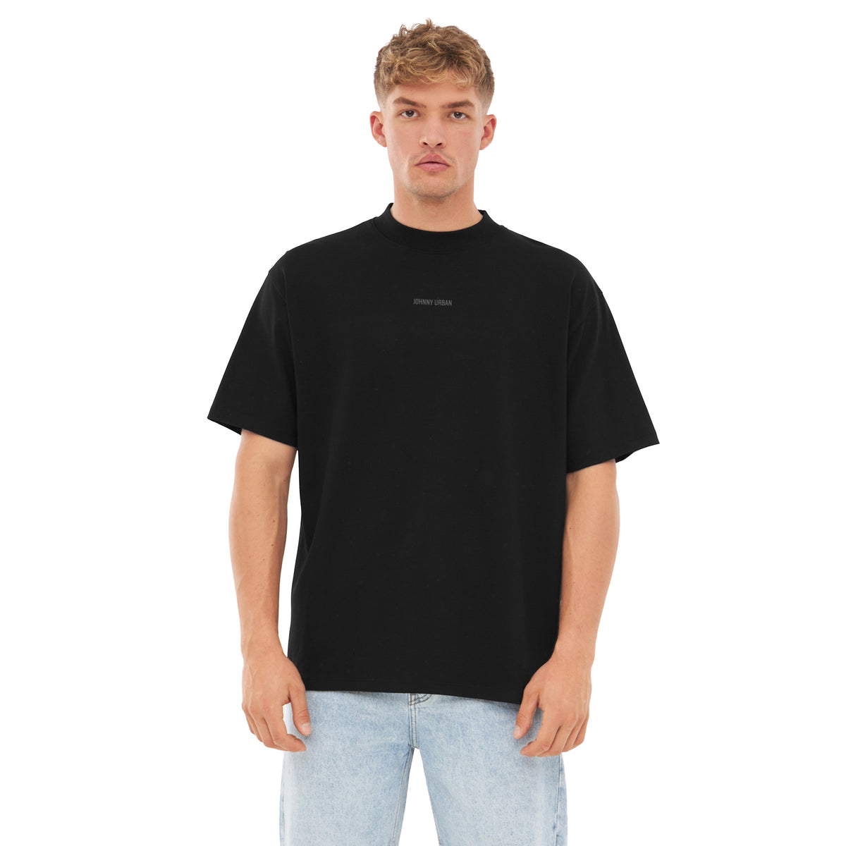 Mann trägt schwarzes Oversized-T-Shirt 'Sammy Johnny Urban' mit kleinem Aufdruck, helle Jeans