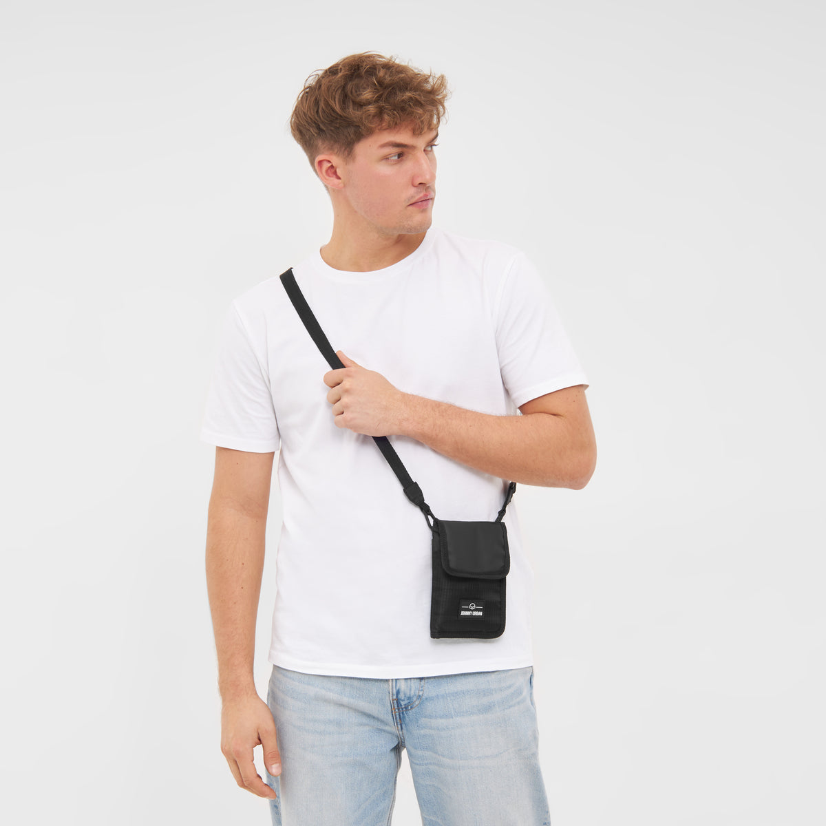 Mann trägt schwarzes Portemonnaie 'Troy' zum Umhängen über weißem T-Shirt und blauen Jeans