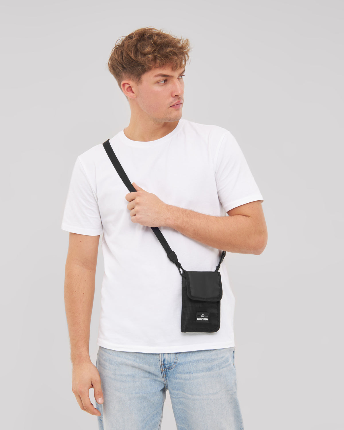 Mann trägt schwarzes Portemonnaie 'Troy' zum Umhängen über weißem T-Shirt und blauen Jeans
