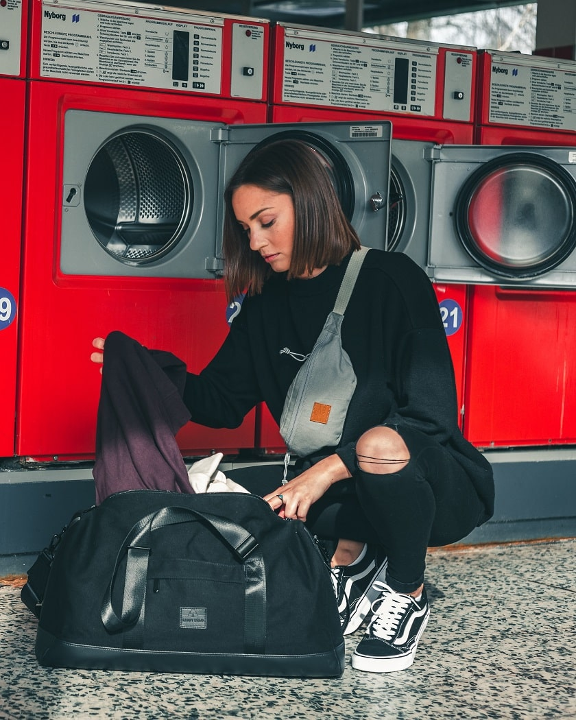 Eine Frau im Waschsalon, die schmutzige Wäsche aus ihrer Tasche holt.
