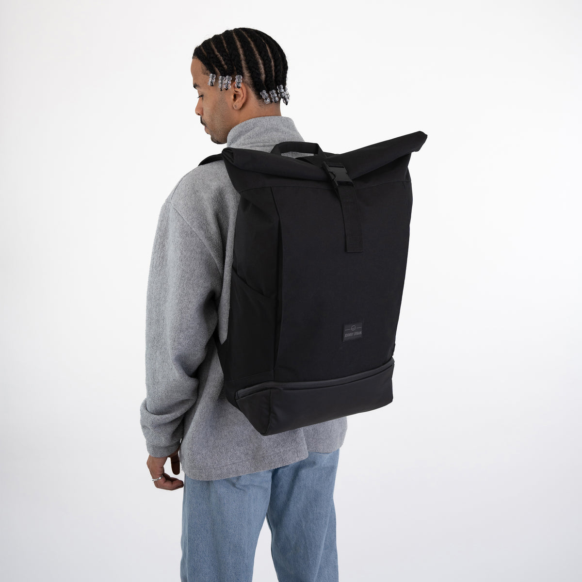 Mann trägt schwarzen Rolltop Rucksack Allen XL von Johnny Urban, graues Sweatshirt, blaue Jeans