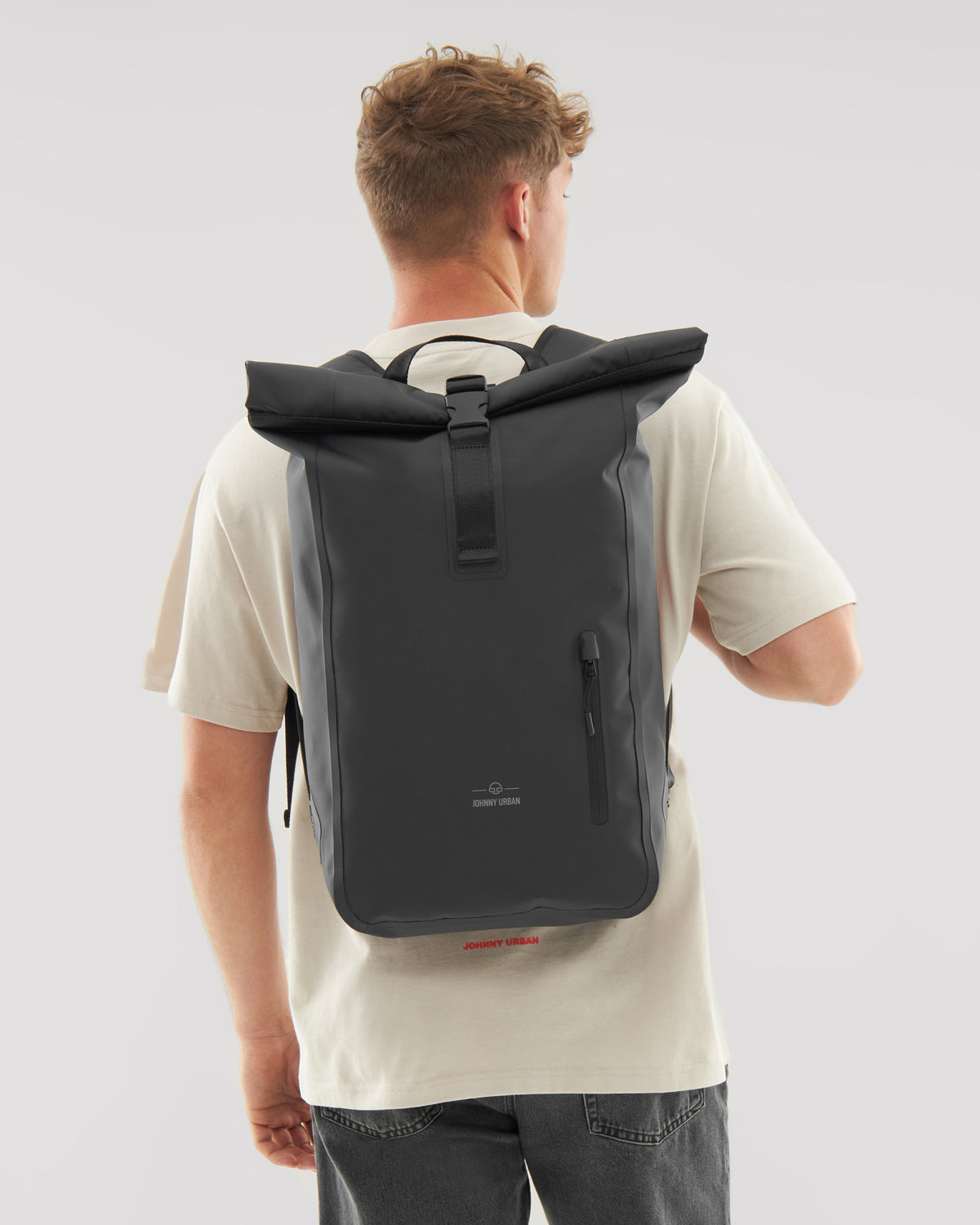 Mann von hinten mit wasserfestem schwarzen Rolltop Rucksack 'Conor' von Johnny Urban
