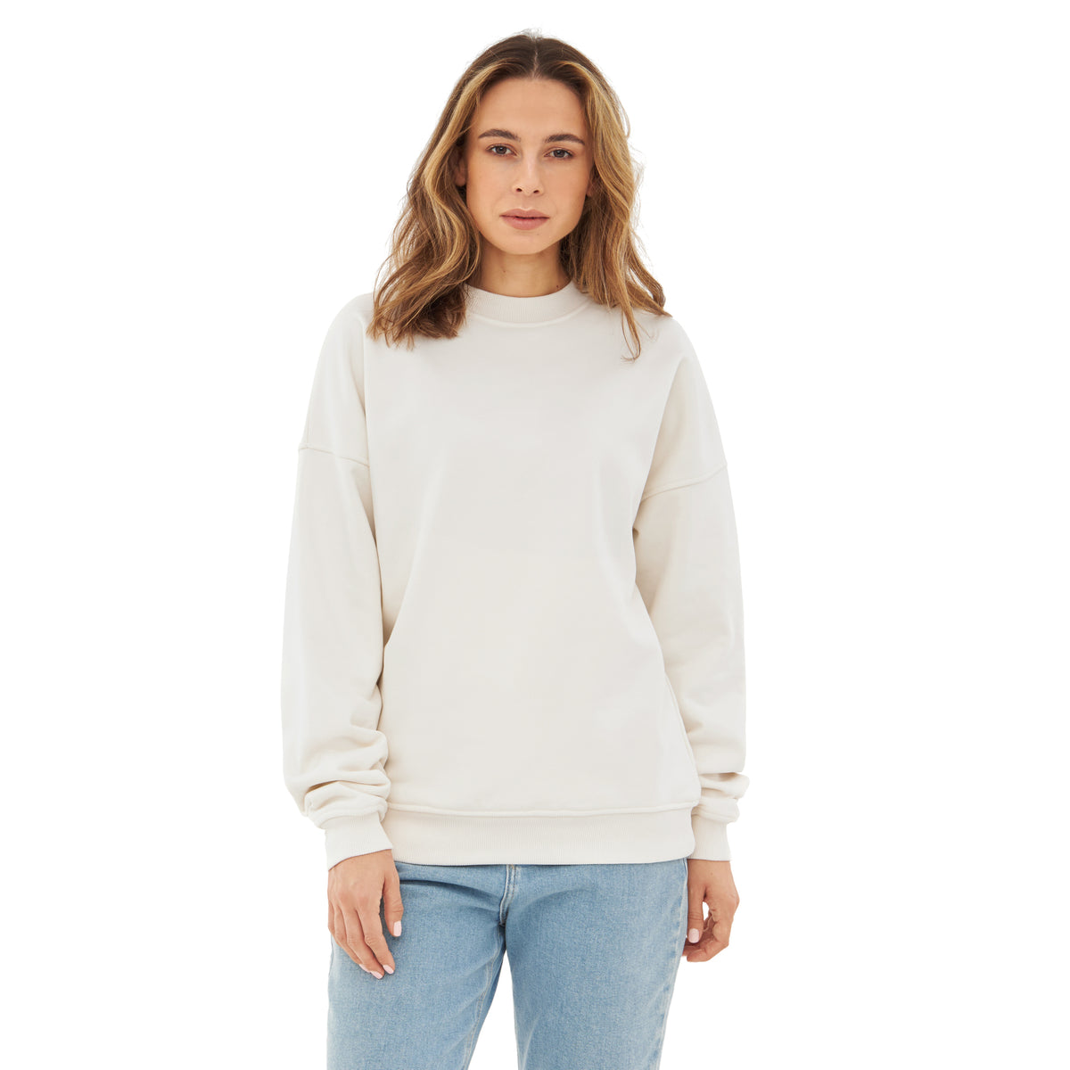 Frau trägt oversized weißen Crewneck 'Carter' Sweatshirt mit langen Ärmeln und blauen Jeans