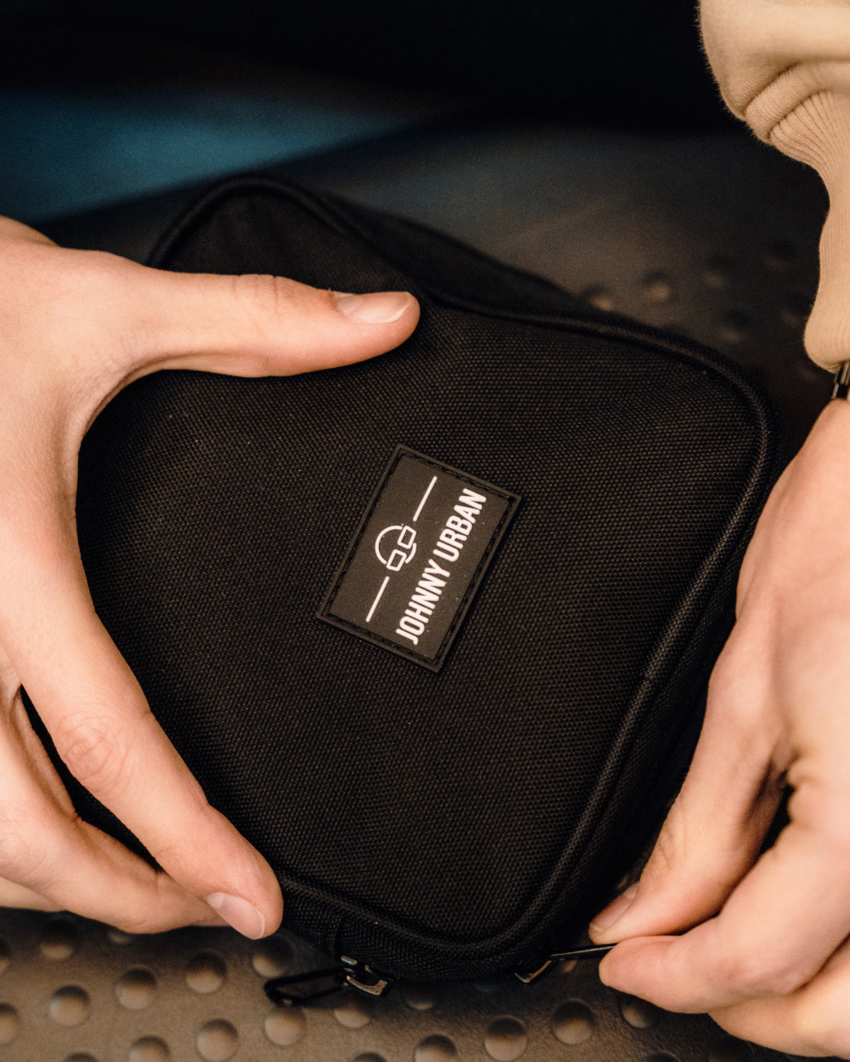 Schwarzer Tech Organizer 'Ted' von Johnny Urban in rechteckiger Form aus robustem Material, gehalten von zwei Händen