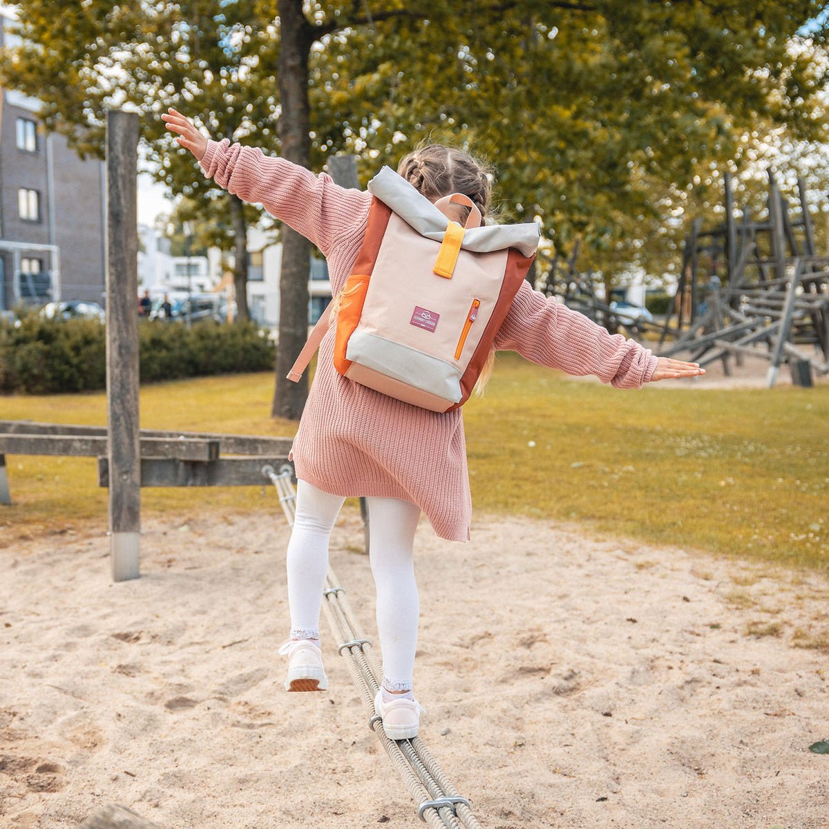 Mädchen balanciert auf Seil im Park mit rosa Rolltop Kinderrucksack 'Aaron' von Johnny Urban