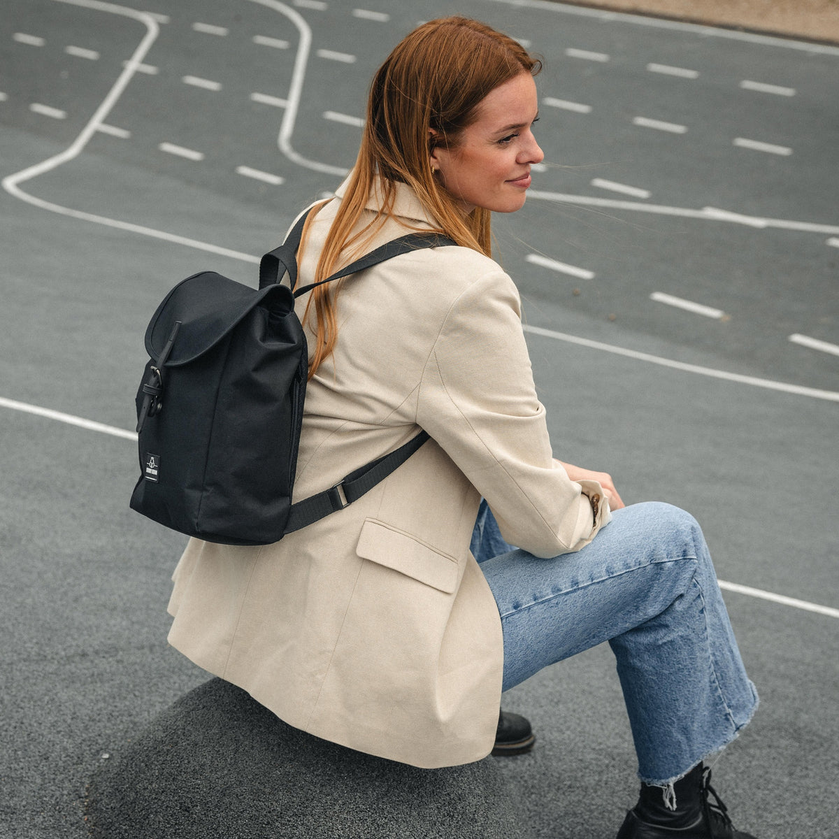 Frau sitzt auf Straße mit kleinem schwarzen Rucksack Damen 'Romy' von Johnny Urban