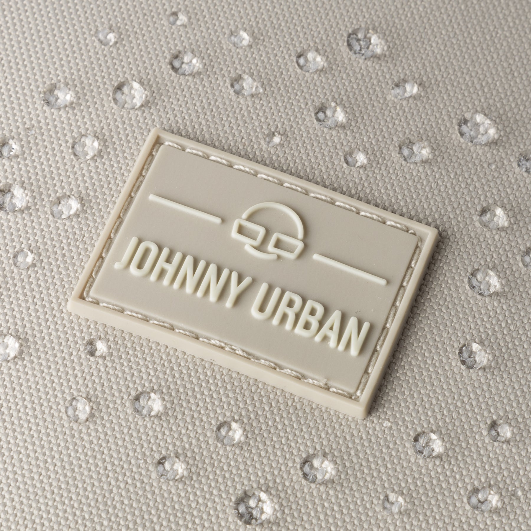 Nahaufnahme des Johnny Urban Logos auf Stoff mit Wasserperlen, zeigt wasserfesten Rucksack 'Nico'