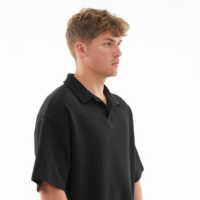 Mann trägt schwarzes Herren-Poloshirt mit kurzem Arm und offenem Kragen, seitliche Ansicht