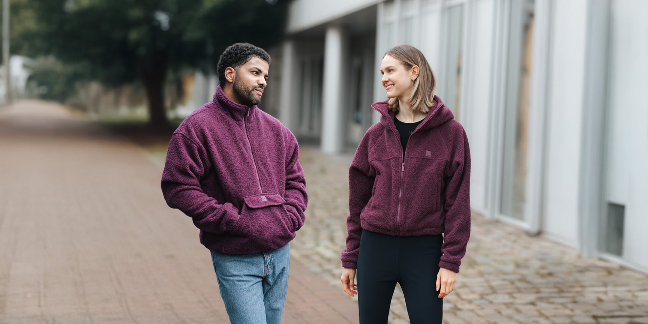 Mann und Frau schauen sich an und tragen die neuen Fleecejacken von Johnny Urban.