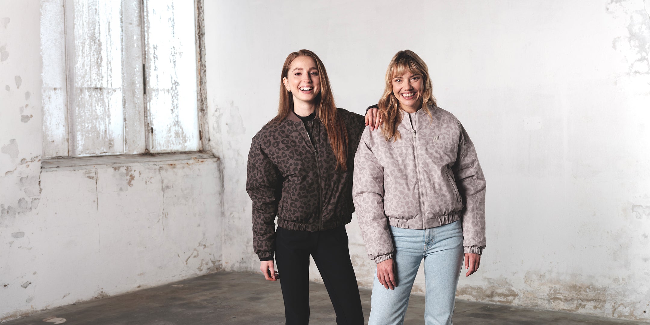 Zwei Frauen stehen nebeneinander, lächeln dabei und tragen die Johnny Urban Bomberjacke im Leo Print.