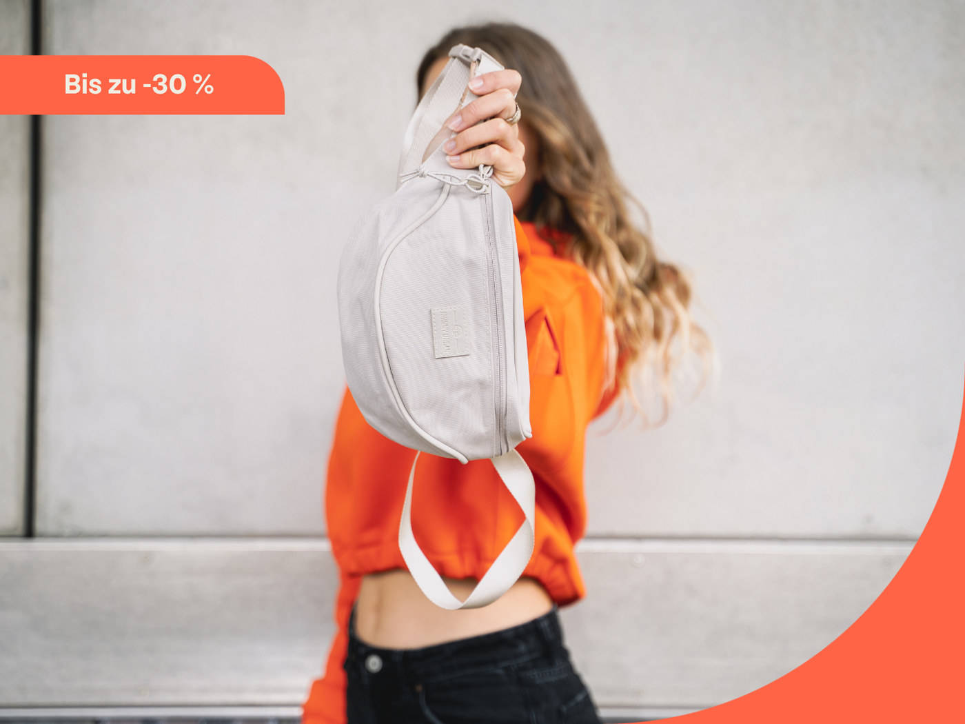 Frau hält Bauchtasche "Ben" in creme in die Kamera.