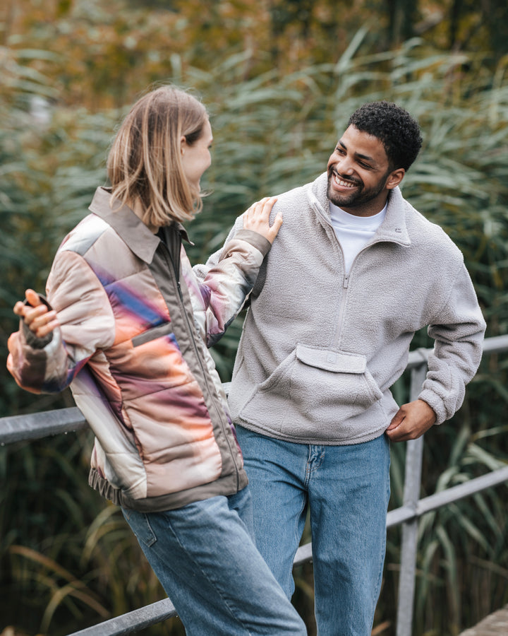 Frau und Mann in Johnny Urban-Halfzip-Fleecepullover und Wendejacke vor einem Waldhintergrund. 