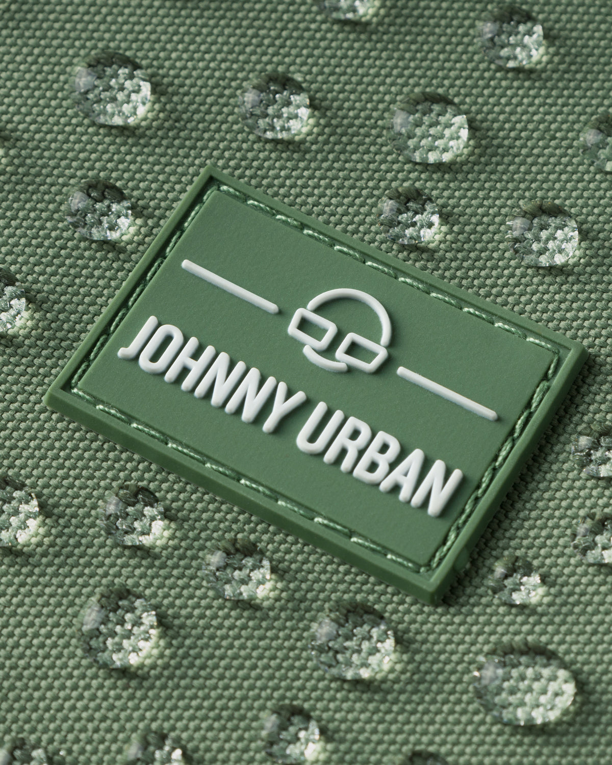 Naheinstellung eines wasserabweisenden grünen Johnny Urban Labels auf Stoff mit Wassertropfen