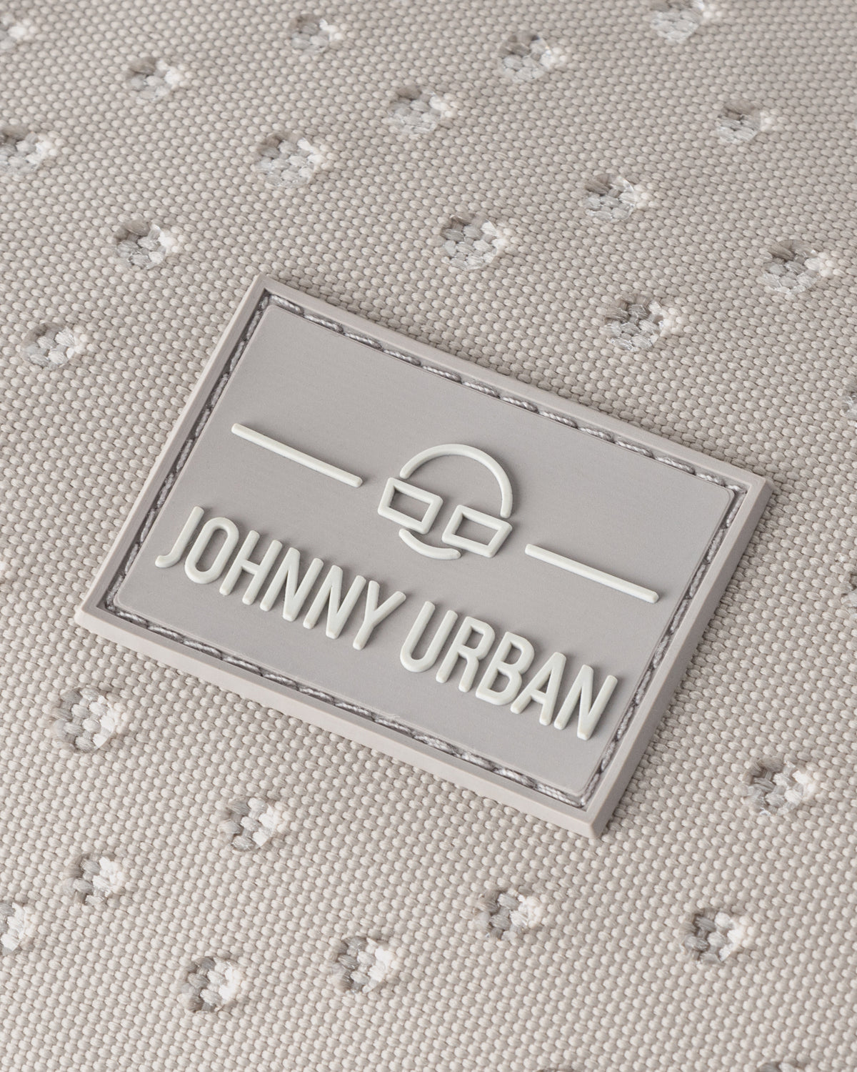 Grau-weißes, wasserabweisendes Material mit feinem Punktemuster und Johnny Urban Logo-Patch