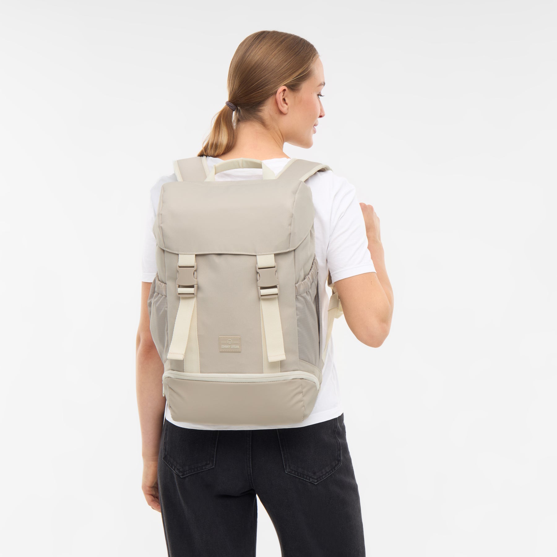 Frau von hinten mit sandfarbenem Rucksack 'Nico' von Johnny Urban, weißes T-Shirt, schwarze Hose