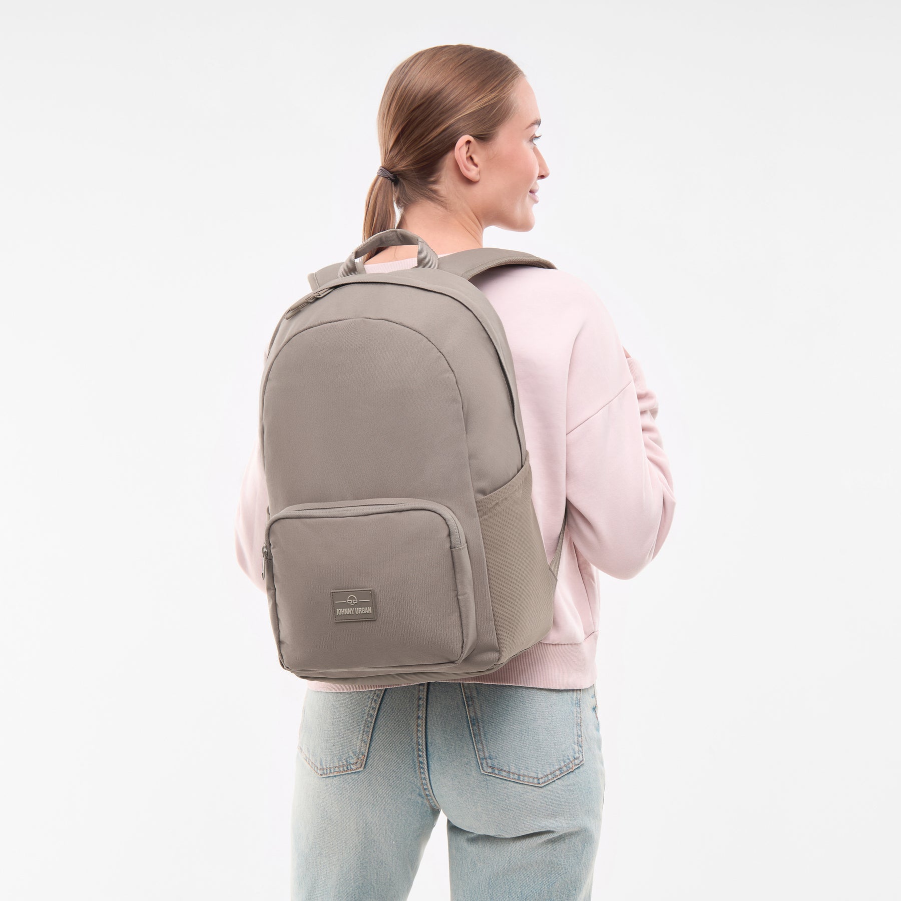 Frau mit Zopf trägt den Johnny Urban Rucksack 'Mo' in desert grey, seitlich gesehen