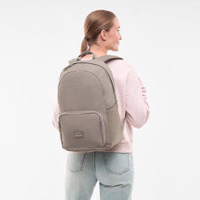 Frau mit Zopf trägt den Johnny Urban Rucksack 'Mo' in desert grey, seitlich gesehen