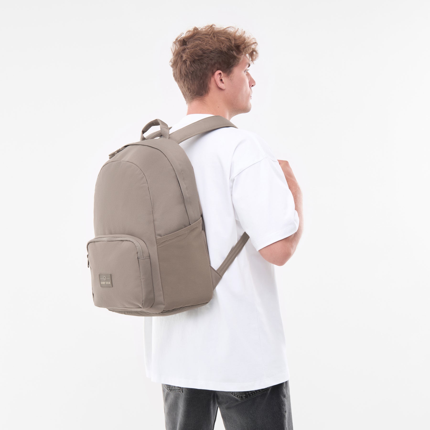 Mann in weißem T-Shirt trägt urbanen 'Mo' Rucksack in desert grey