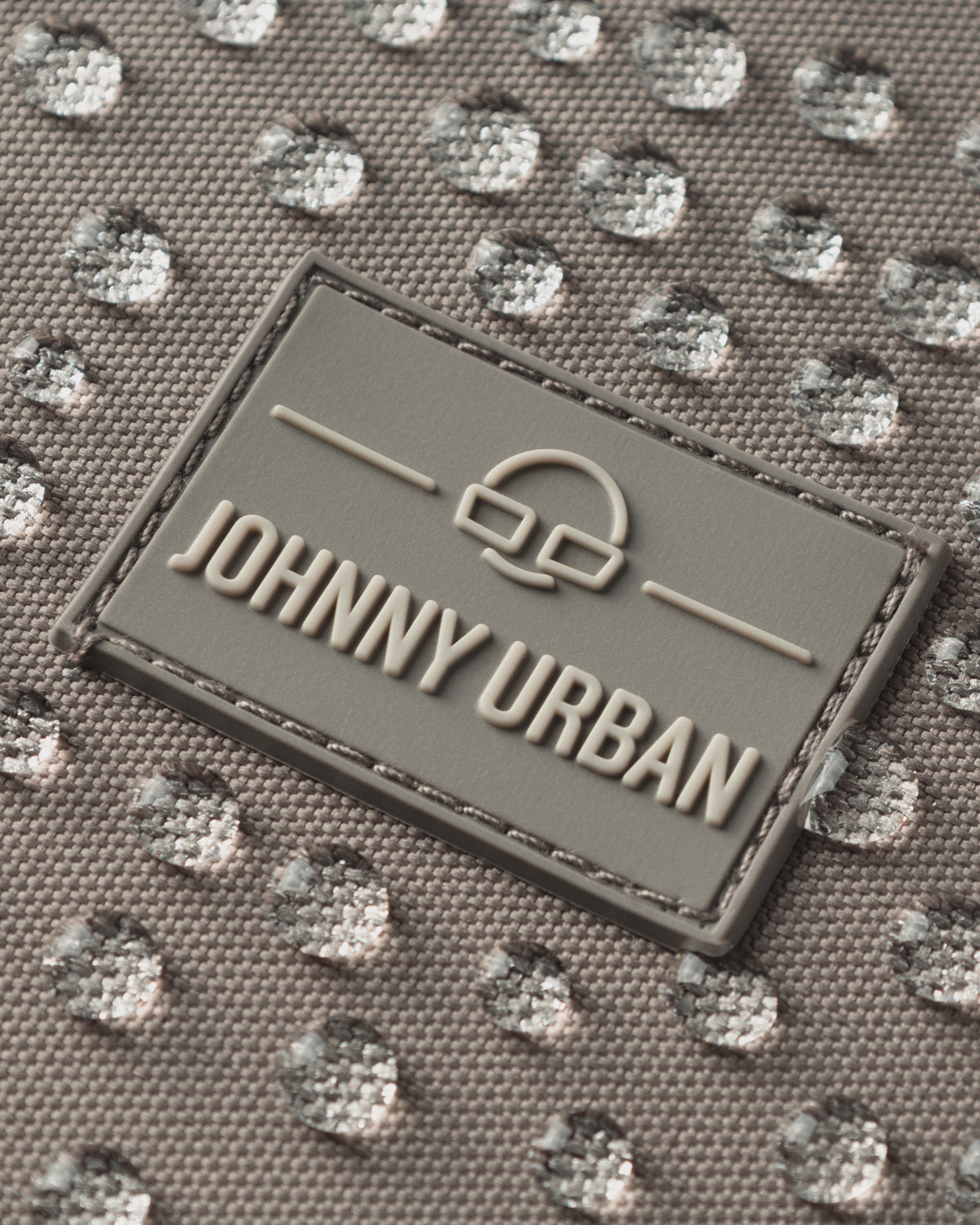 Nahaufnahme des wasserabweisenden Stoffes und Logos des Rucksacks 'Lian' von Johnny Urban in Desert-Grau