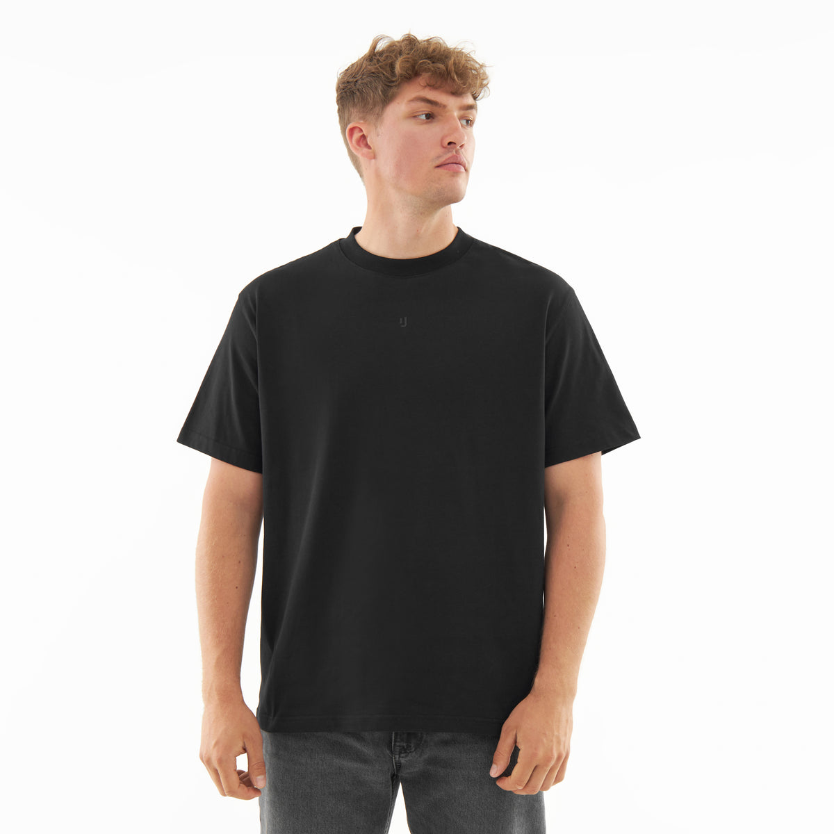Mann trägt schwarzes Oversize-T-Shirt 'Sammy Butterfly' mit kleinem Logo vorn