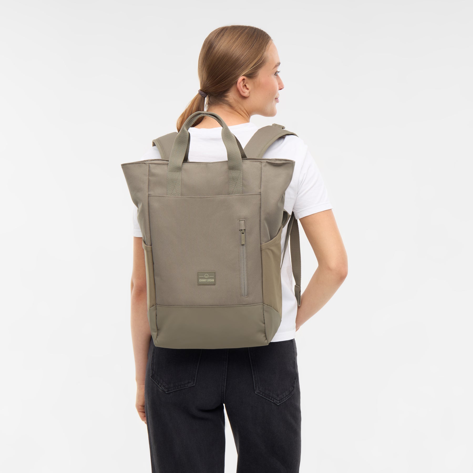 Frau trägt den Wickelrucksack 'Blair' von Johnny Urban in desert-grau, mit Tragegriffen und Reißverschlusstasche vorne
