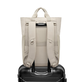 Rückseite der cremefarbenen Wickeltasche 'Blair' mit gepolsterten Trägern auf dem Griff eines schwarzen Reisekoffers