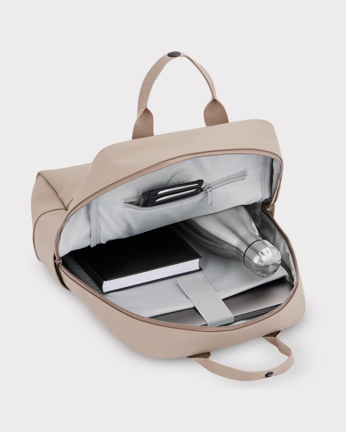 Beiger Damenrucksack 'Hailey' mit offenem Hauptfach, darin eine silberne Trinkflasche, ein schwarzes Buch und ein Laptopfach